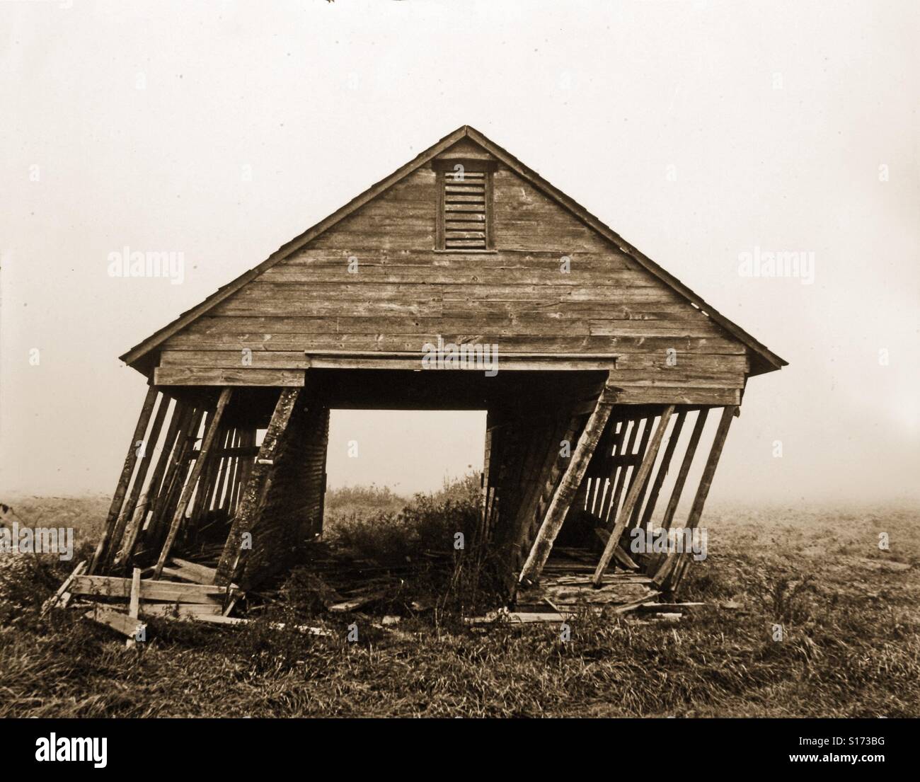 An old barn looks about to fall down as it leans to the right. Sepia toned photo - Smartphone Captured Stock Image
