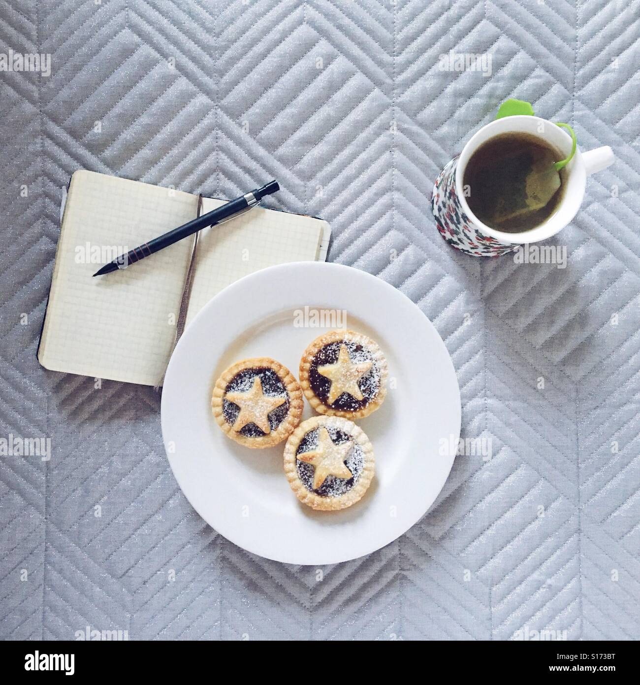Mince pies on a plate, herbal tea and a notebook with pencil - Smartphone Captured Stock Image