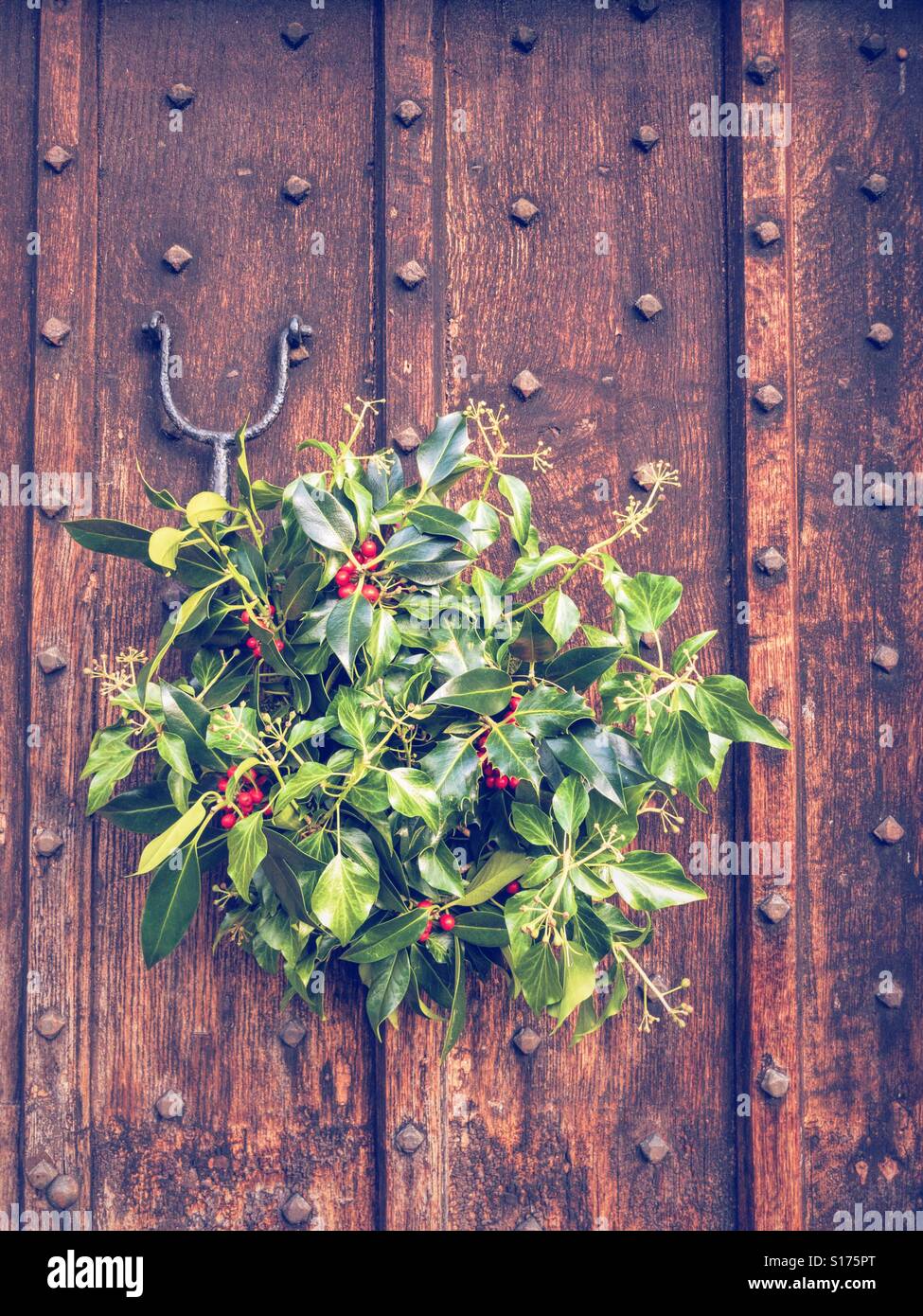 BAKEWELL, ENGLAND - NOVEMBER 4: Holly and mistletoe Christmas wreath hanging on wooden door in Britain. In Bakewell, England. On 4th December 2016. Stock Photo