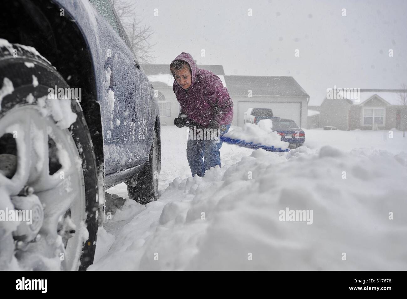 A woman shovels snow in her driveway as snow continues to fall at her home in Franklin, Indiana. Her name is Lana Kotioukova - Smartphone Captured Stock Image