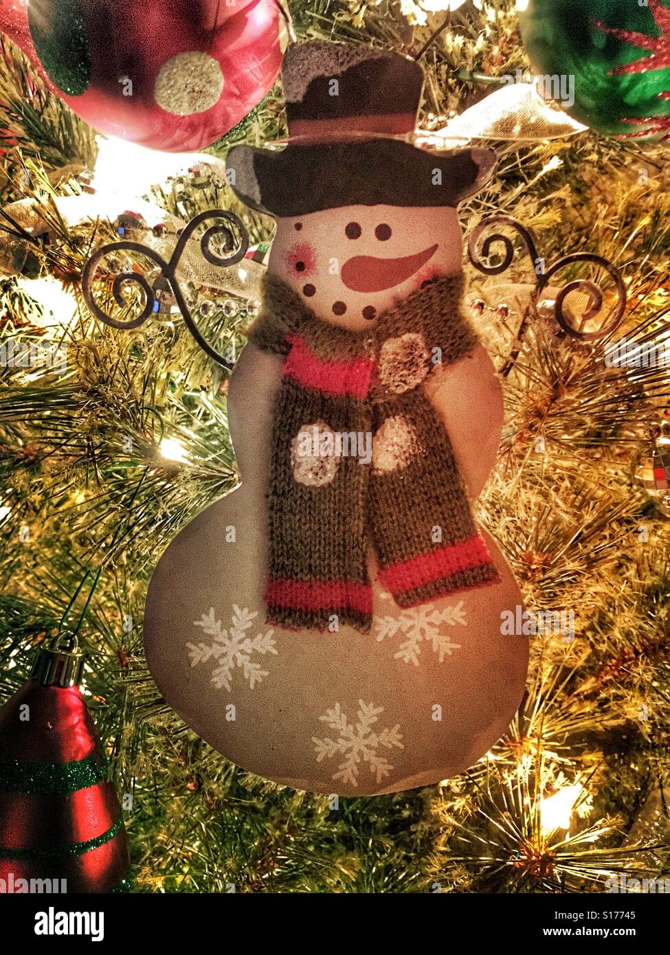 A wooden snowman ornament hanging on a Christmas tree. - Smartphone Captured Stock Image