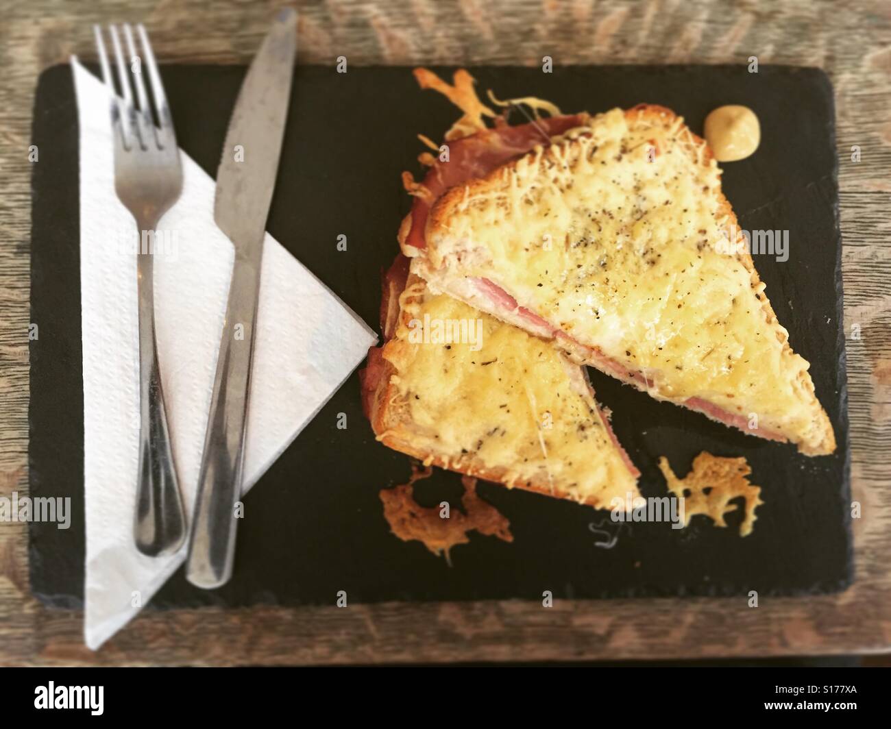A croque monsieur with knife and fork on slate plate Stock Photo