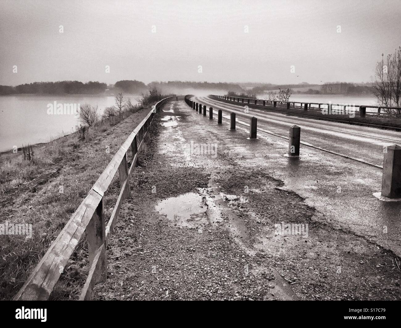 Black and white photo of vehicle causeway across reservoir in the mist Stock Photo
