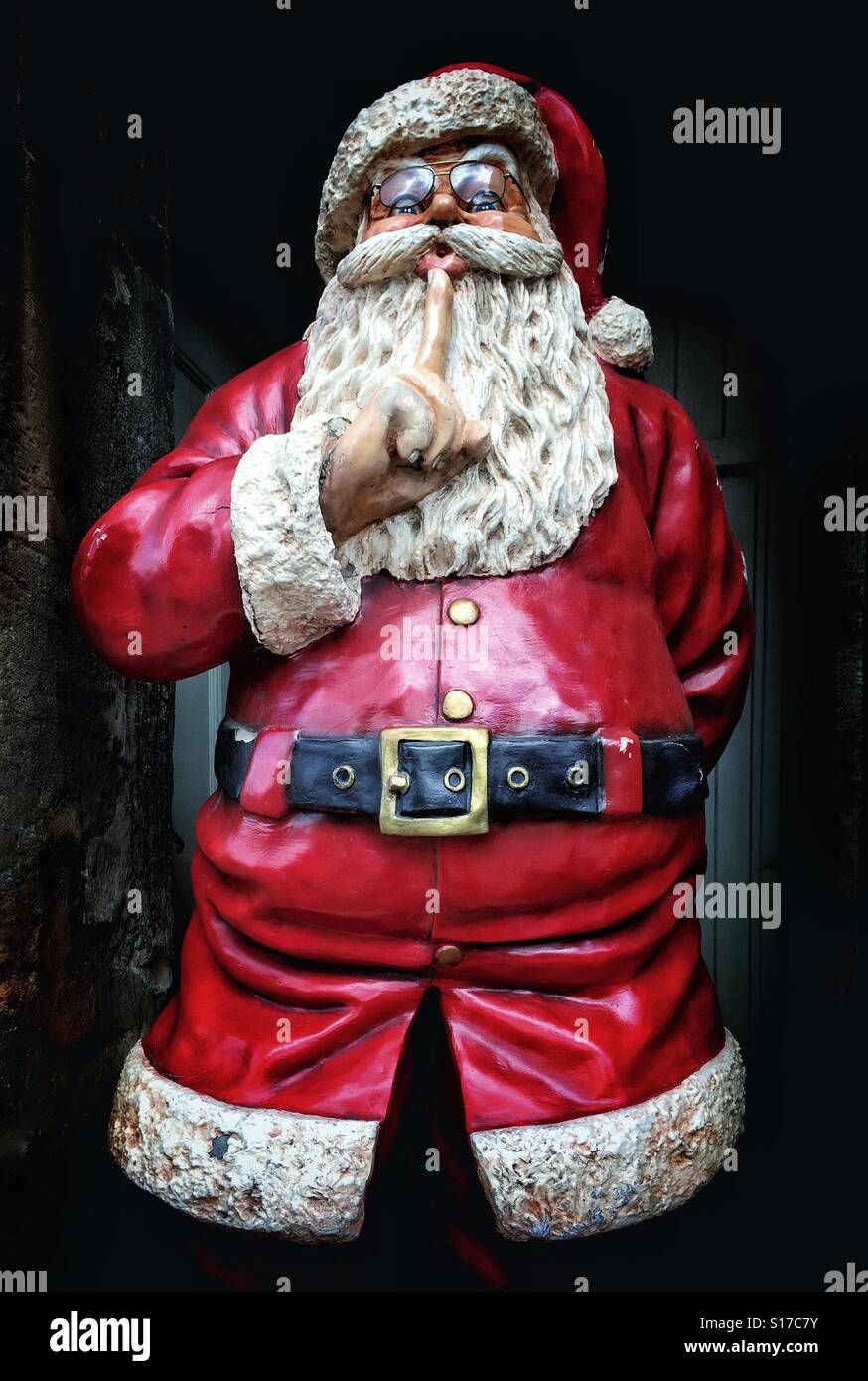 A view looking upwards at a chubby Santa Clause as he stands in a doorway and gestures to all to hush & be quiet. It must be Christmas time! Photo Credit - © COLIN HOSKINS. Stock Photo