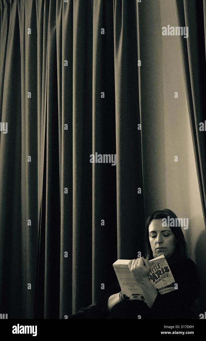 Woman reading a book in a hotel room - Smartphone Captured Stock Image