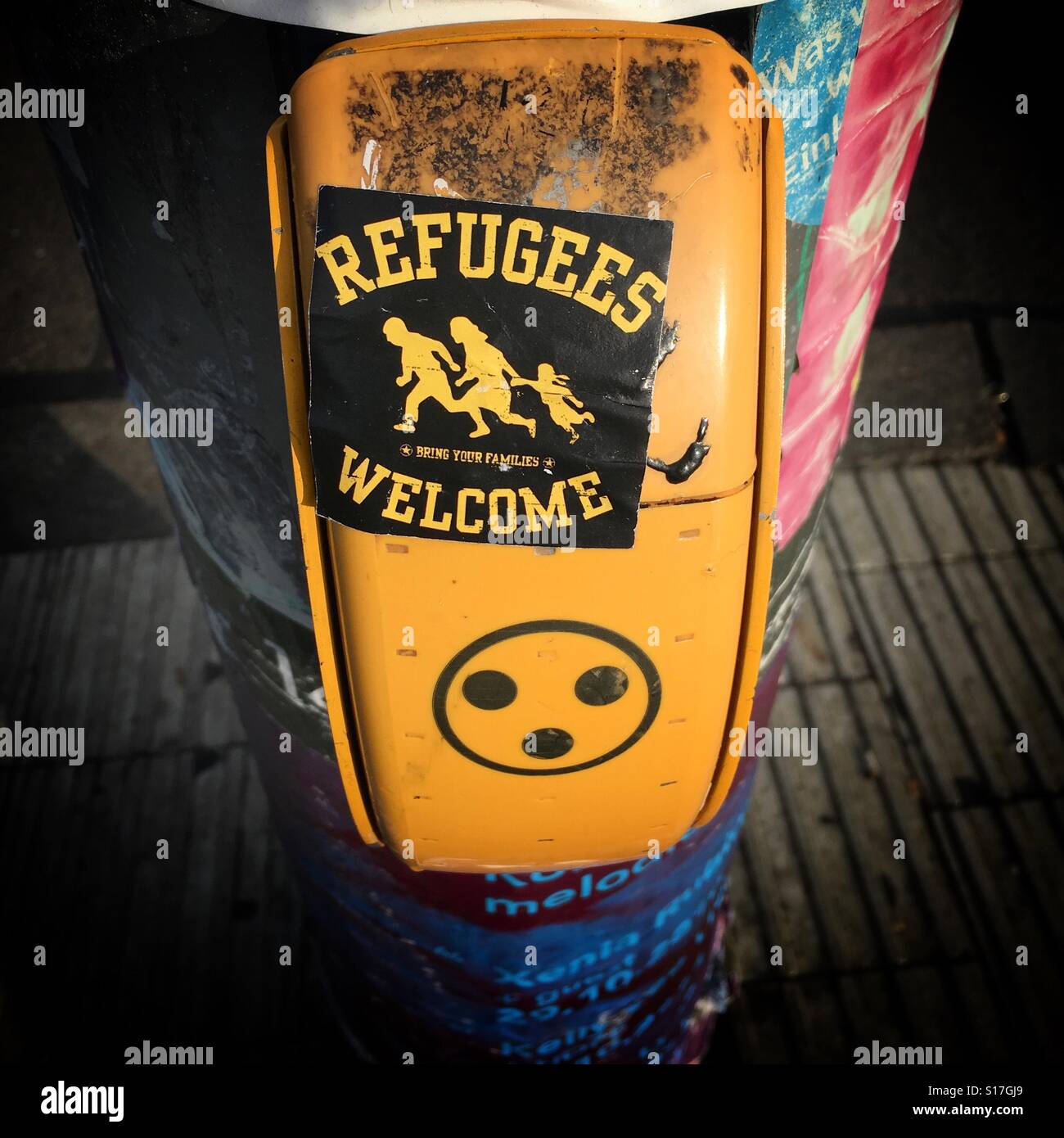 A Refugees Welcome sticker on a traffic signal pole in Berlin, Germany - Smartphone Captured Stock Image