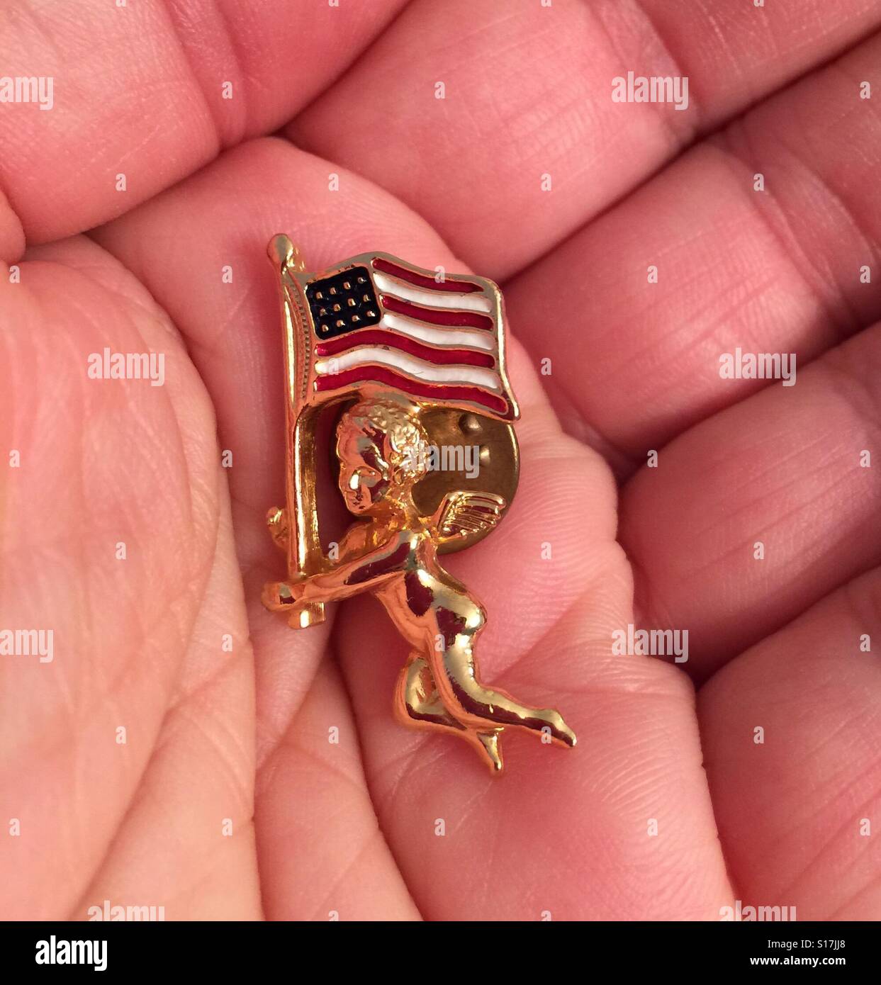A Caucasian hand holding a golden angel pin with an American flag Stock  Photo - Alamy