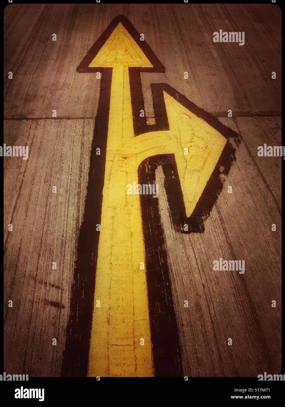 Straight Ahead OR Turn Right ONLY. Yellow direction signs painted on the concrete floor of a multi story car park. Photo Credit - © COLIN HOSKINS. - Smartphone Captured Stock Image