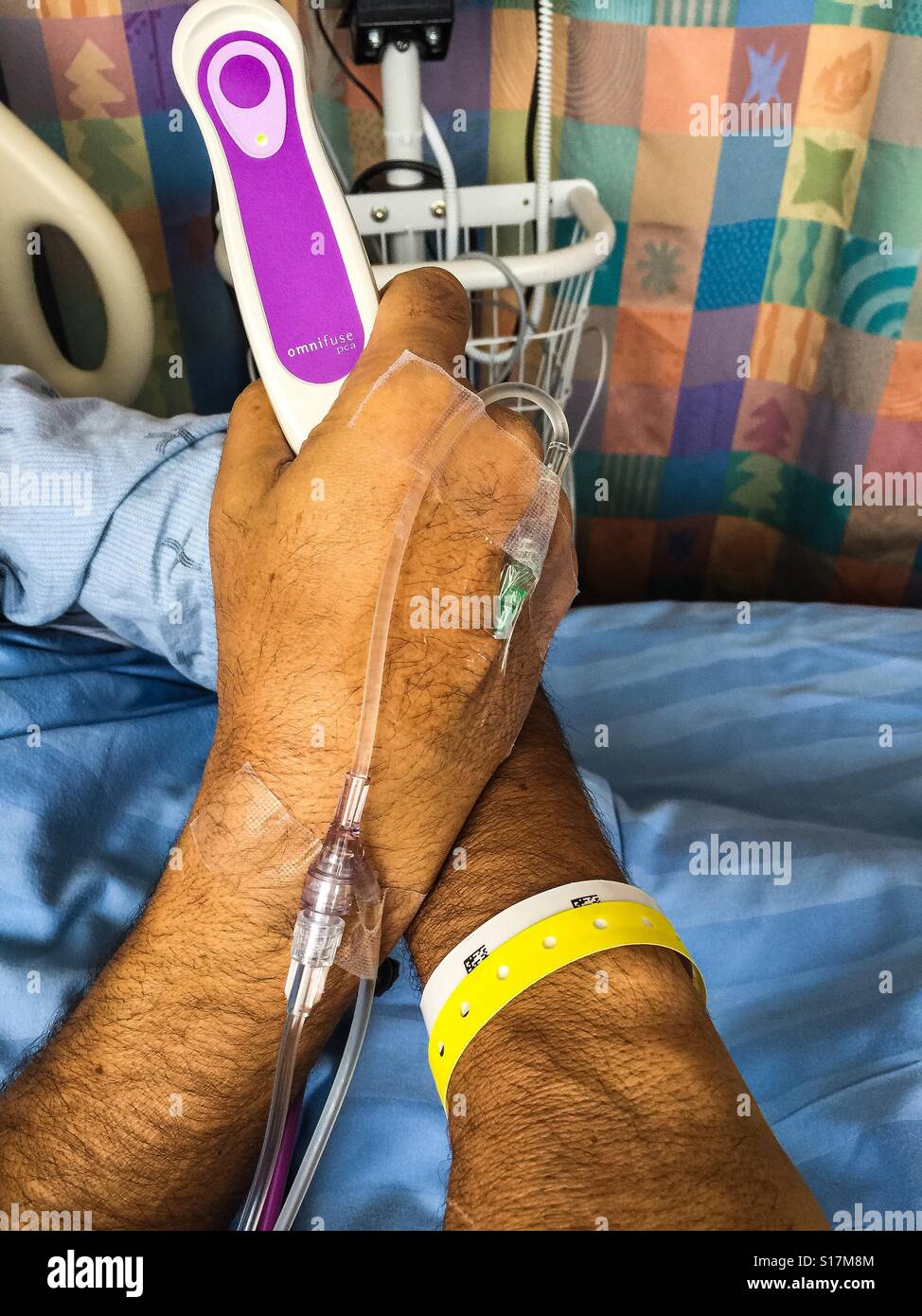 Hospital bed with a patient holding a morphine pump in his hand. Post-surgical pain management with a hand-held device. Alternative to epidural. Time limited to prevent OD. Modern - Smartphone Captured Stock Image