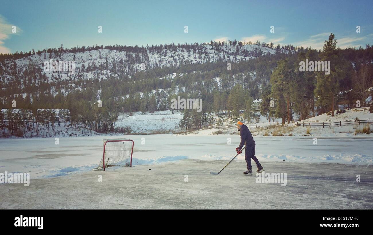 Young man playing ice hockey on a frozen pond - Smartphone Captured Stock Image