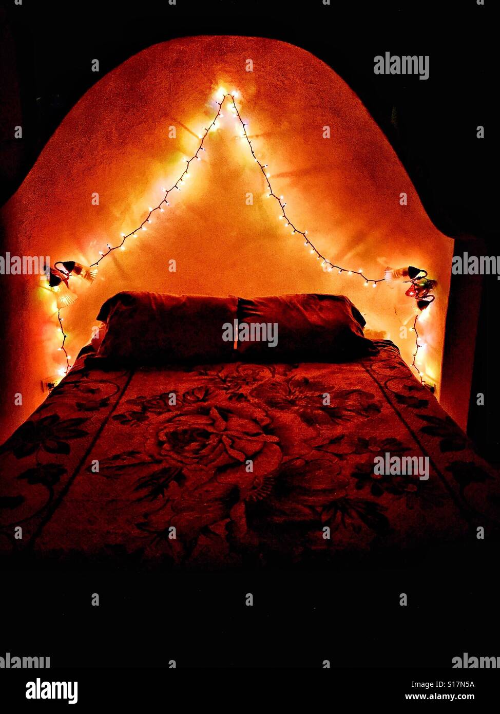 Christmas lights over the bed add a festive and romantic touch to the
