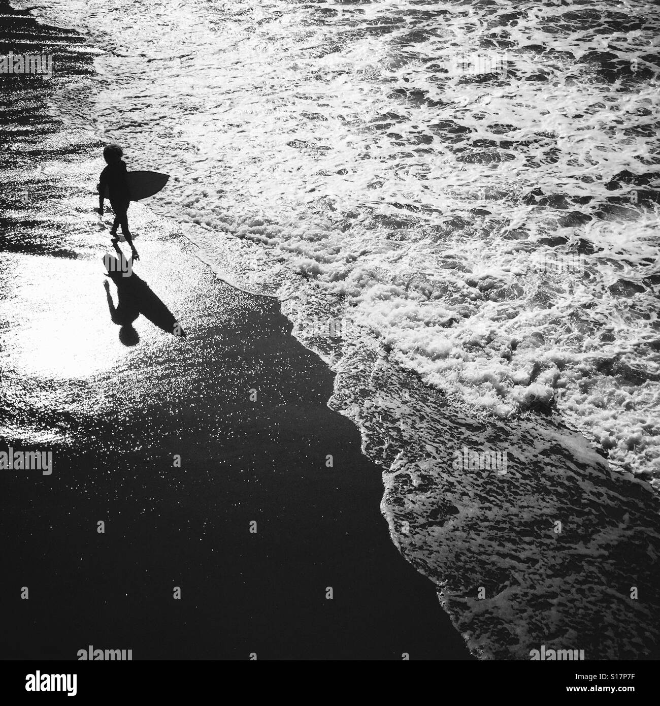 A surfer waking on the beach. Manhattan Beach, California USA. Stock Photo