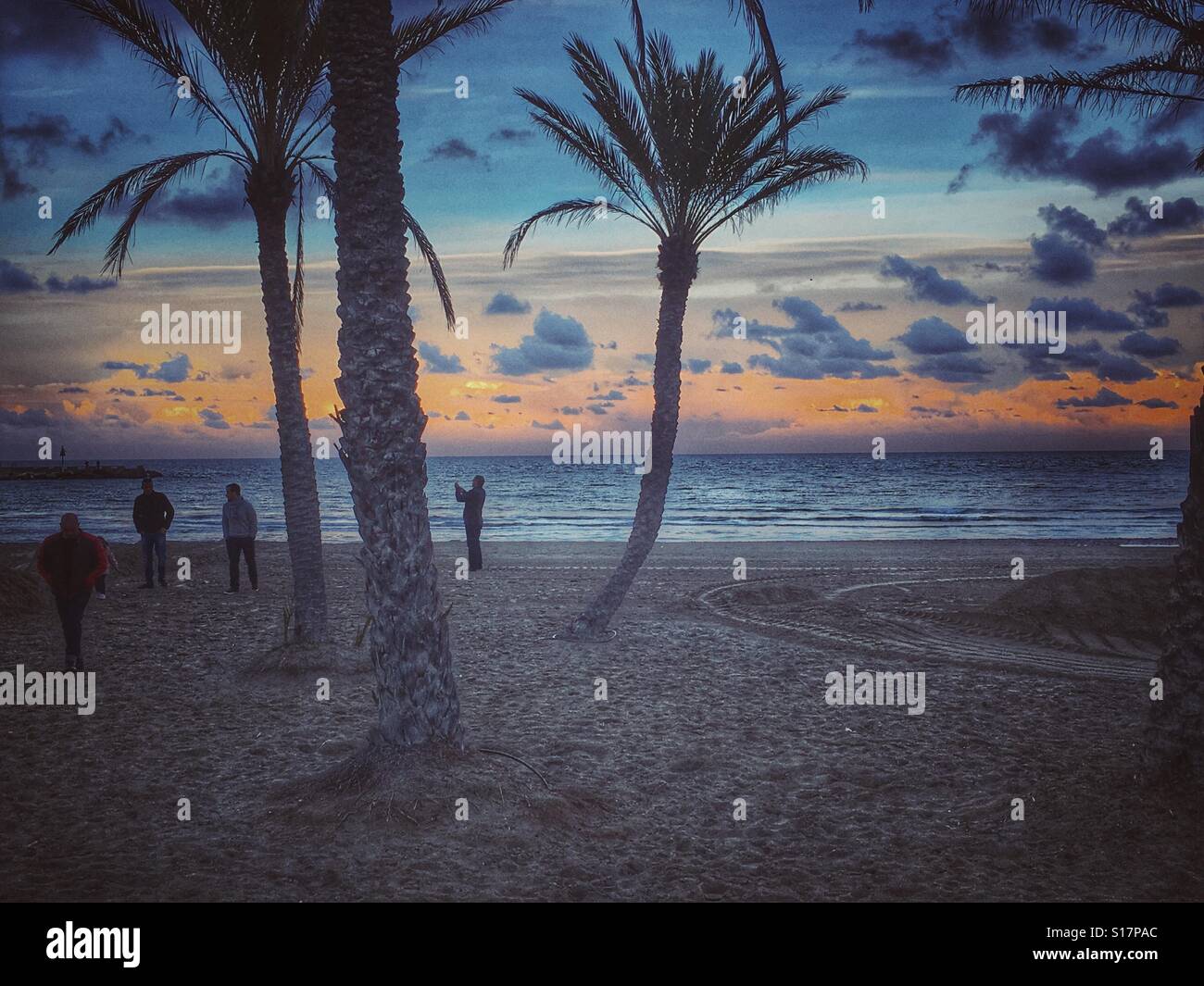 People on beach in winter at sunset - Smartphone Captured Stock Image