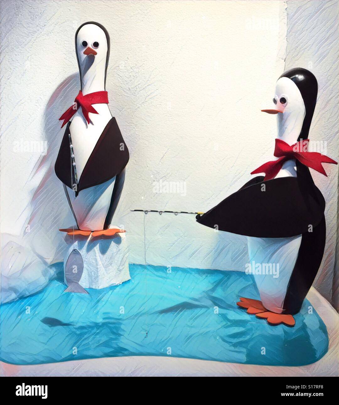 Two penguin figures that look like bowling pins standing above a pool of water - Smartphone Captured Stock Image