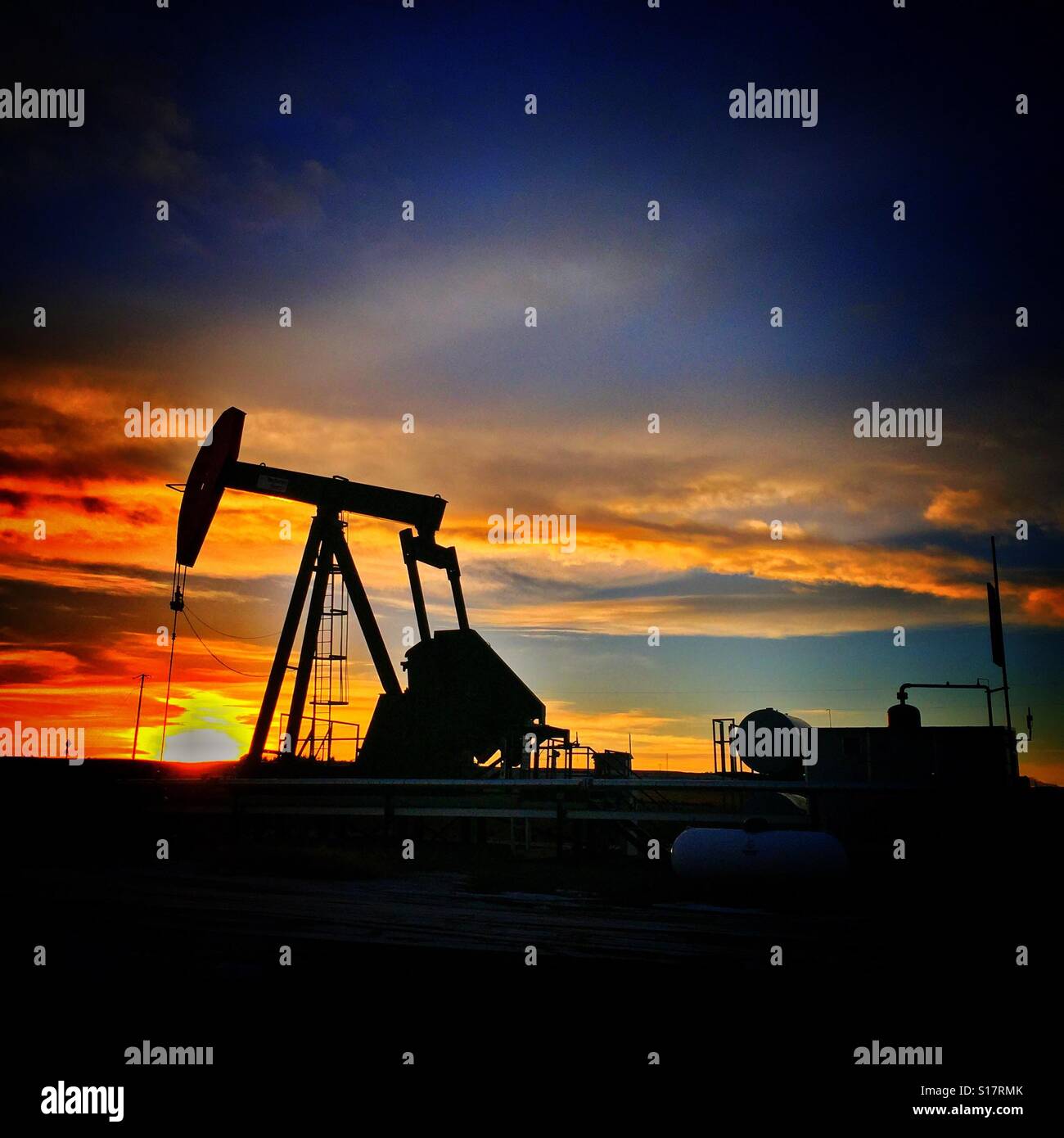 Oil well pump jack silhouette and the setting sun - Smartphone Captured Stock Image