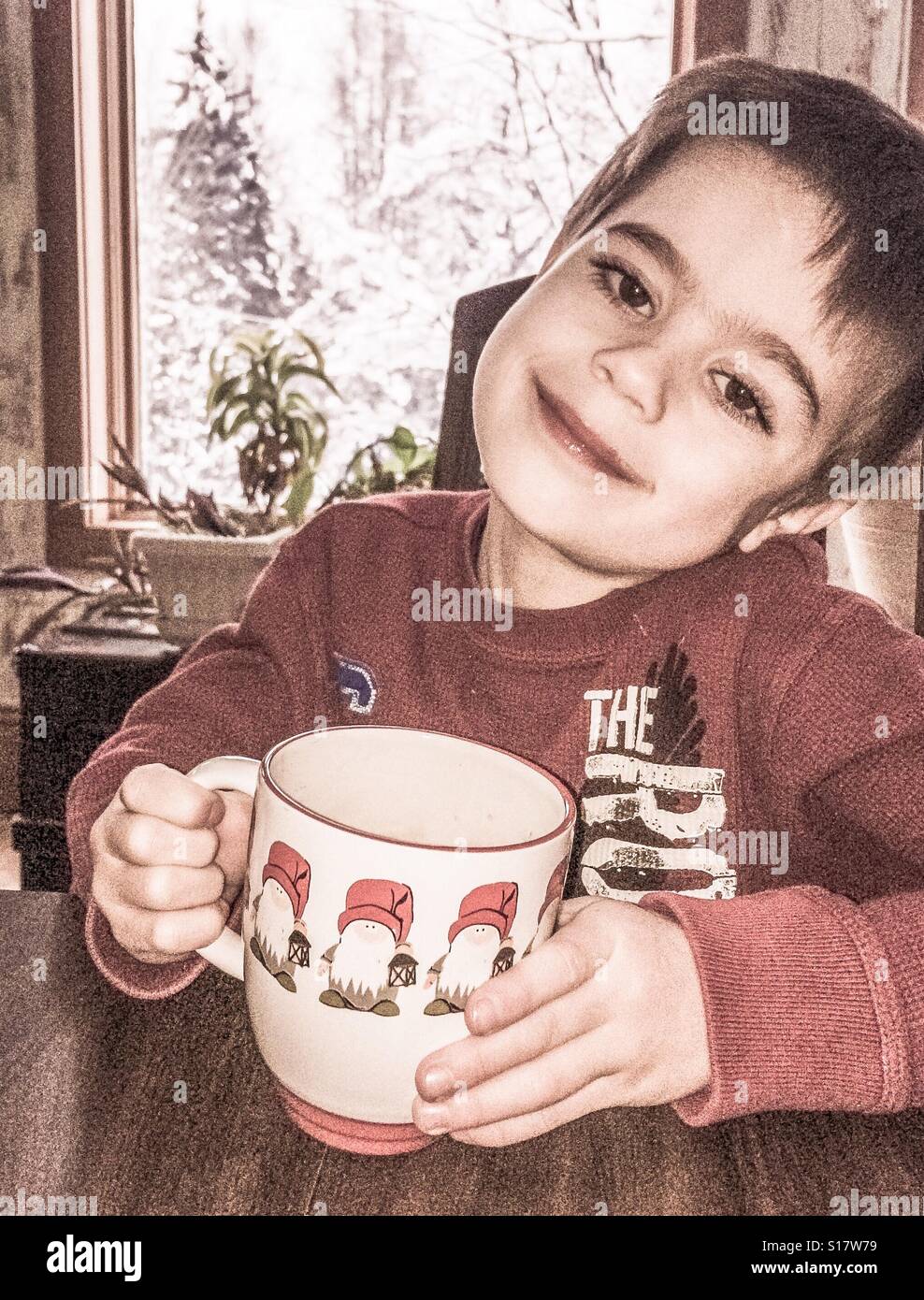 A six year old boy enjoys hot cocoa in a Swedish Santa mug. - Smartphone Captured Stock Image