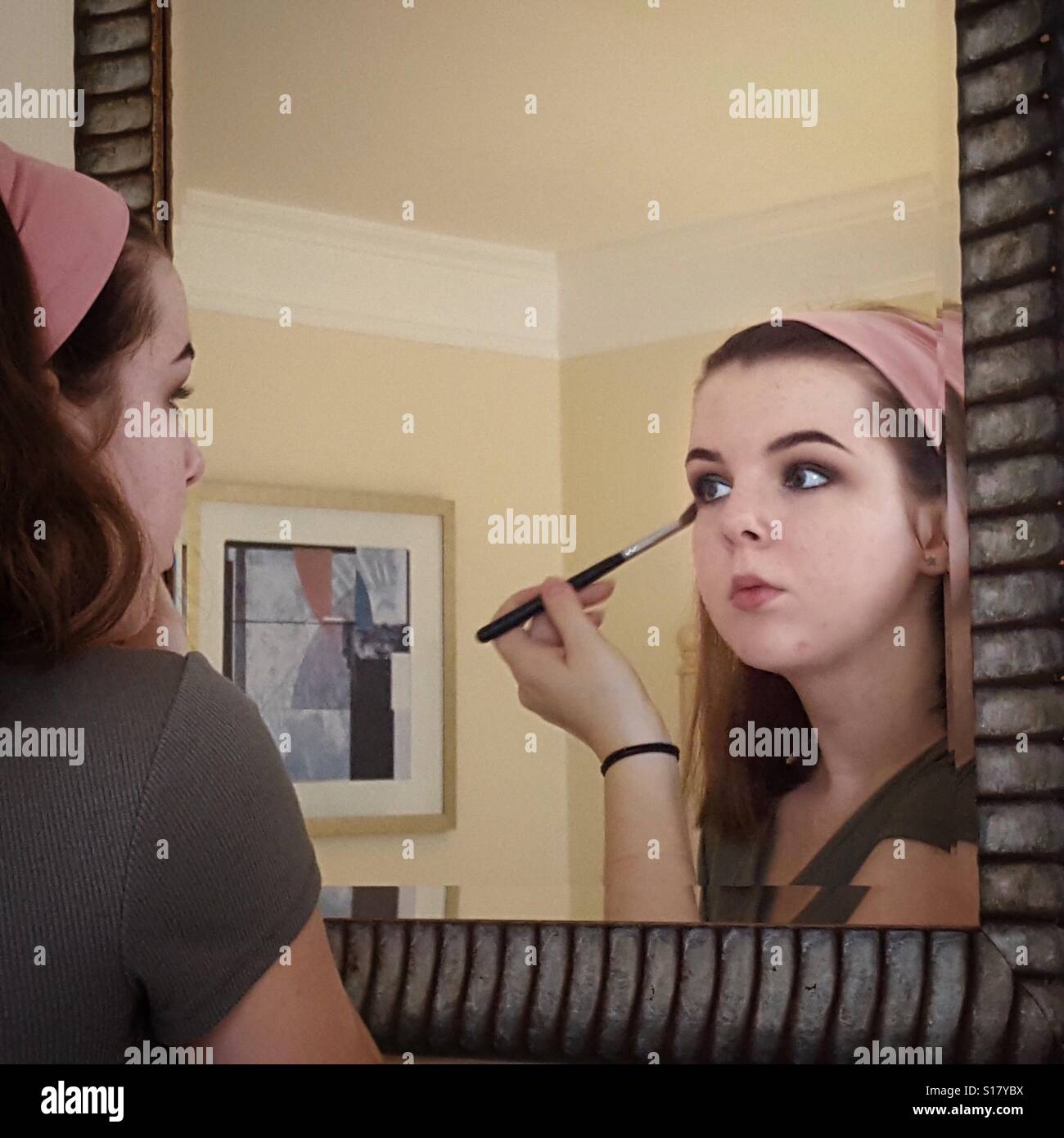 Girl applying eye makeup in a mirror Stock Photo Alamy