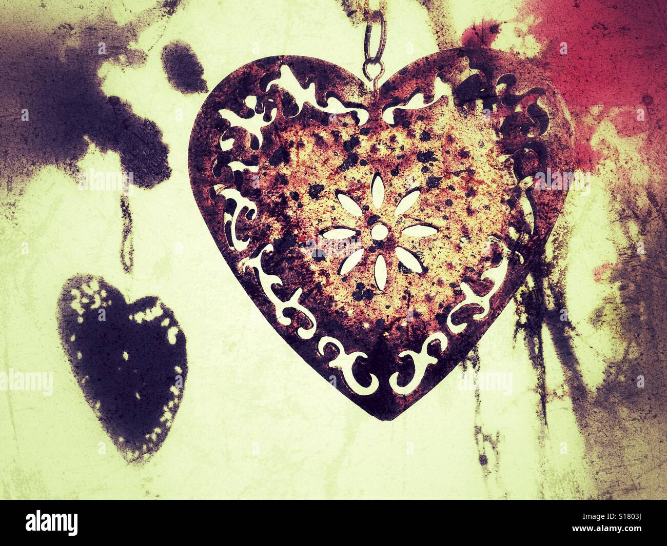 Rusty heart hanging in a bougainvillea plant against a white wall - Smartphone Captured Stock Image