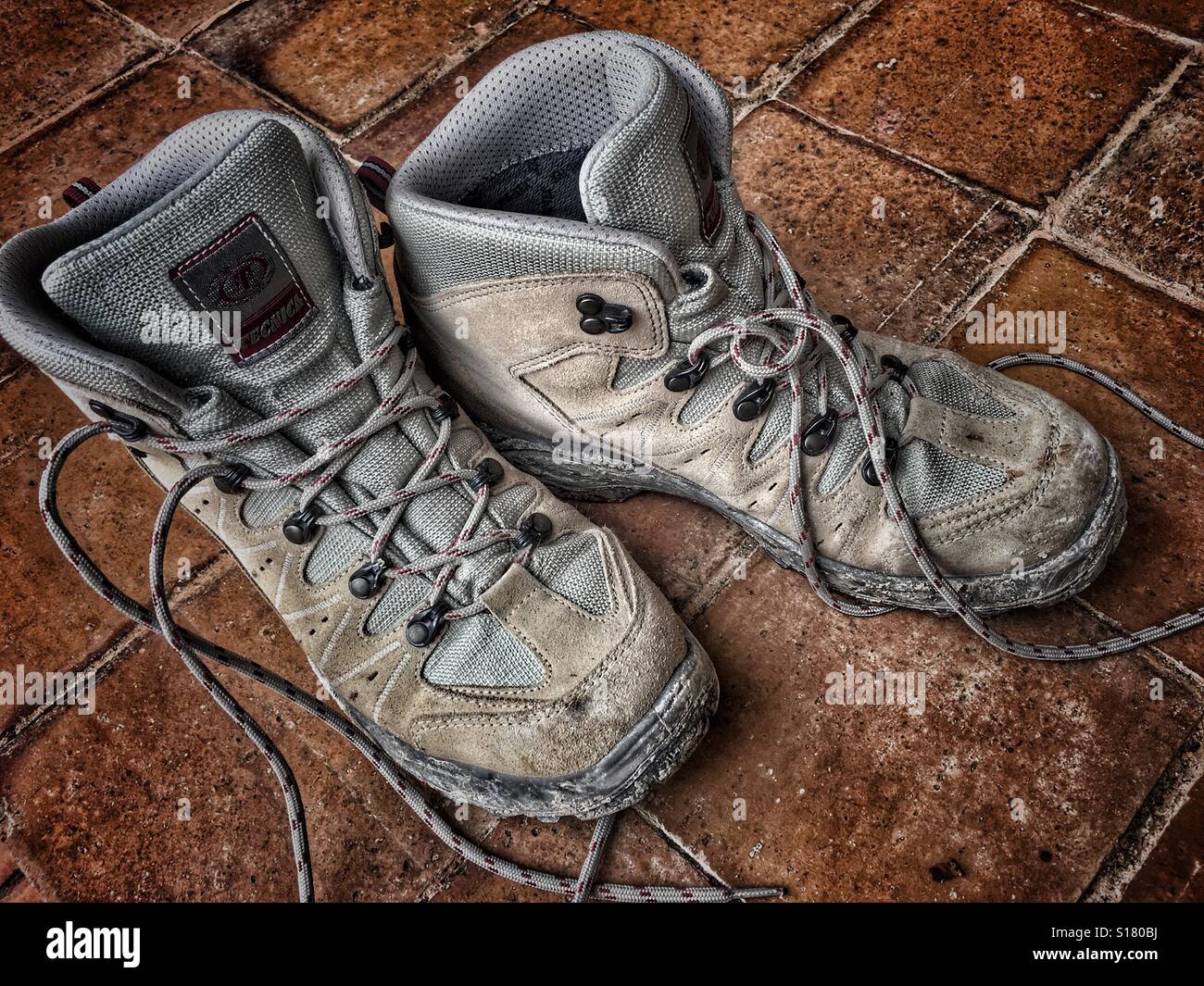 Muddy hiking boots on a tiled floor - Smartphone Captured Stock Image