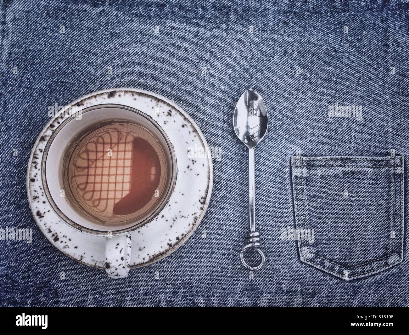 Cup of tea and a spoon on a jeans tablecloth with a pocket - Smartphone Captured Stock Image