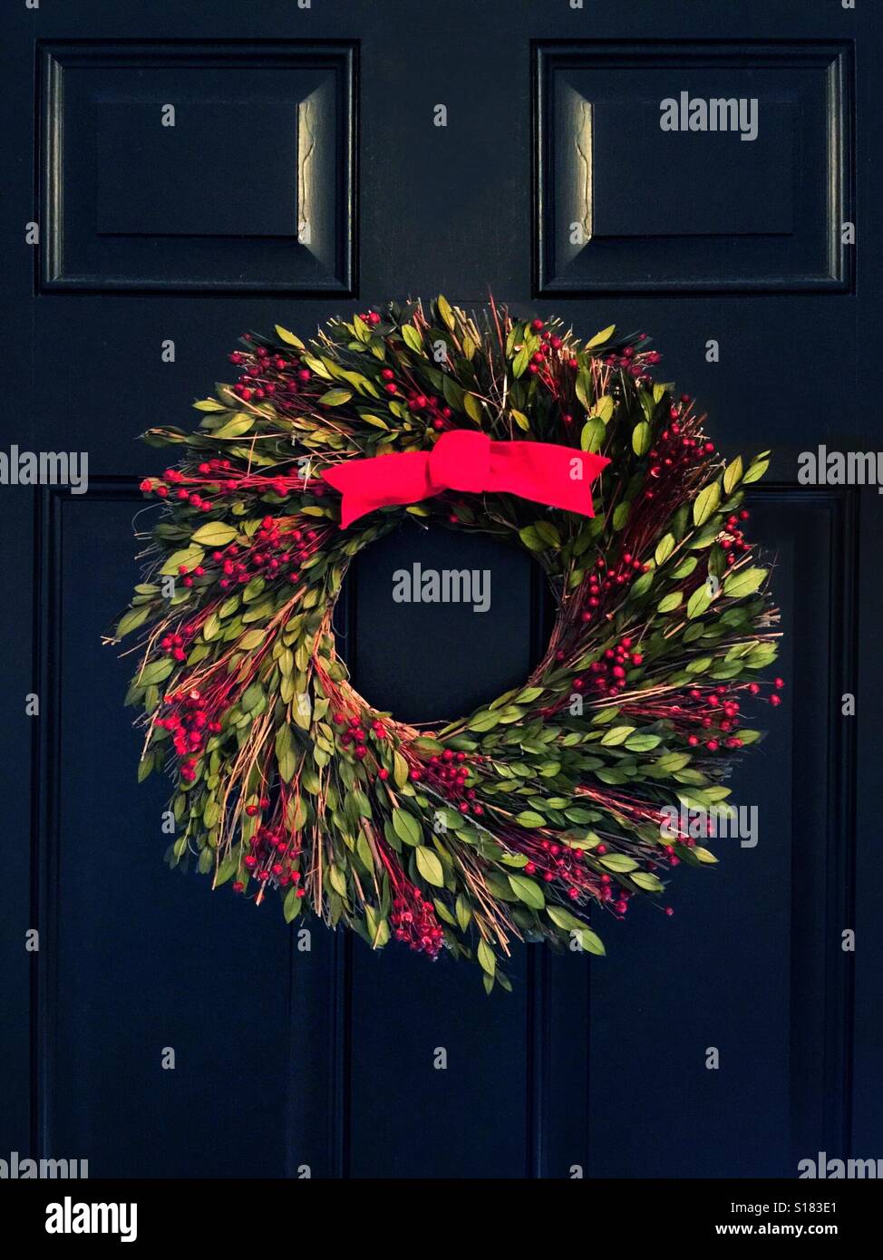A Christmas wreath with a red bow on a black door - Smartphone Captured Stock Image