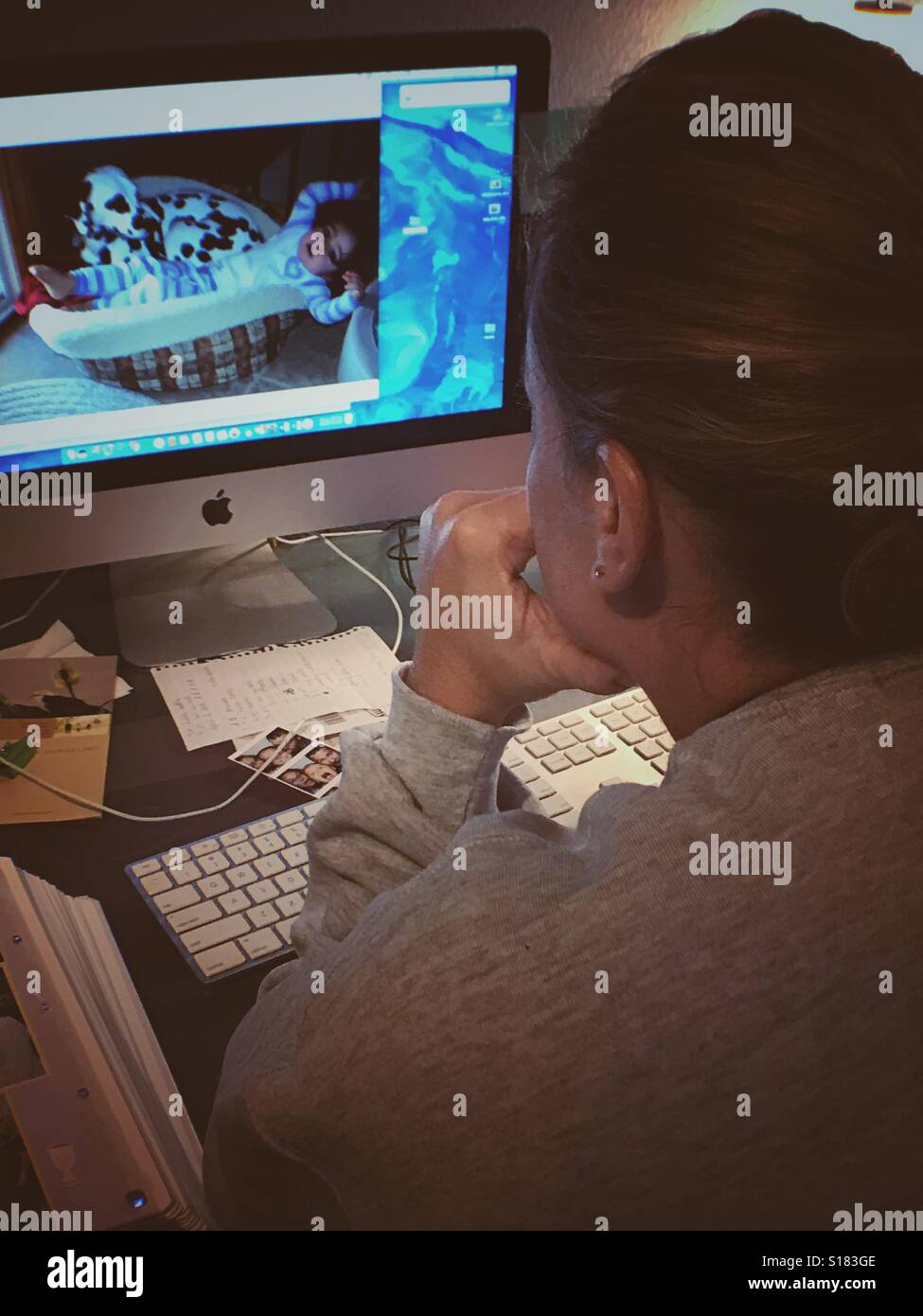 Woman reviews photos on her iMac - Smartphone Captured Stock Image