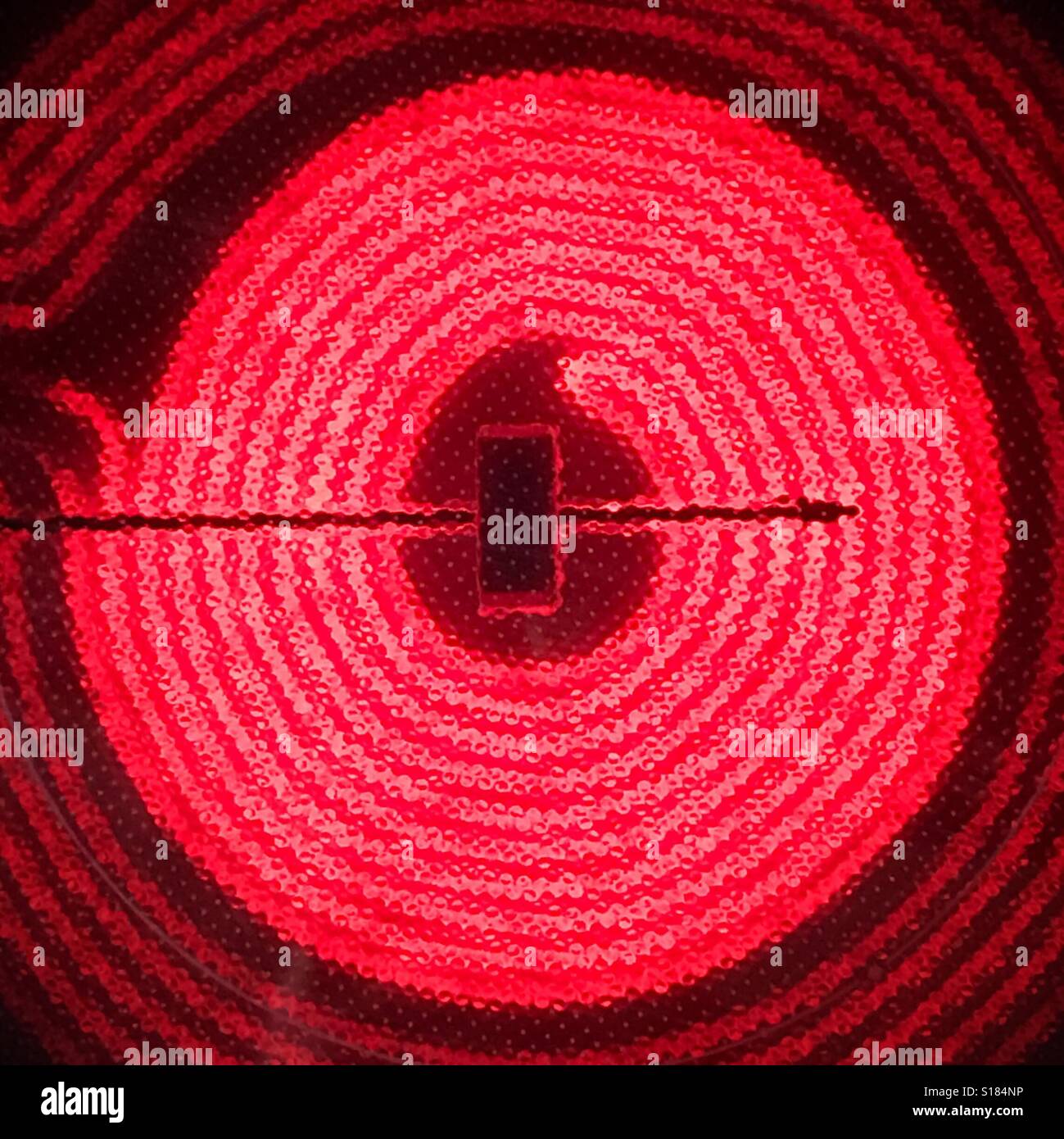Circular heating element on a glass top stove glowing red Stock Photo