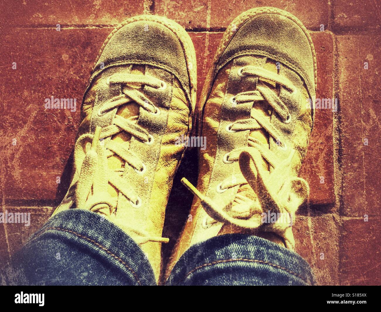 POV blue denim jeans, yellow leather sneakers on a terracotta tiled floor - Smartphone Captured Stock Image