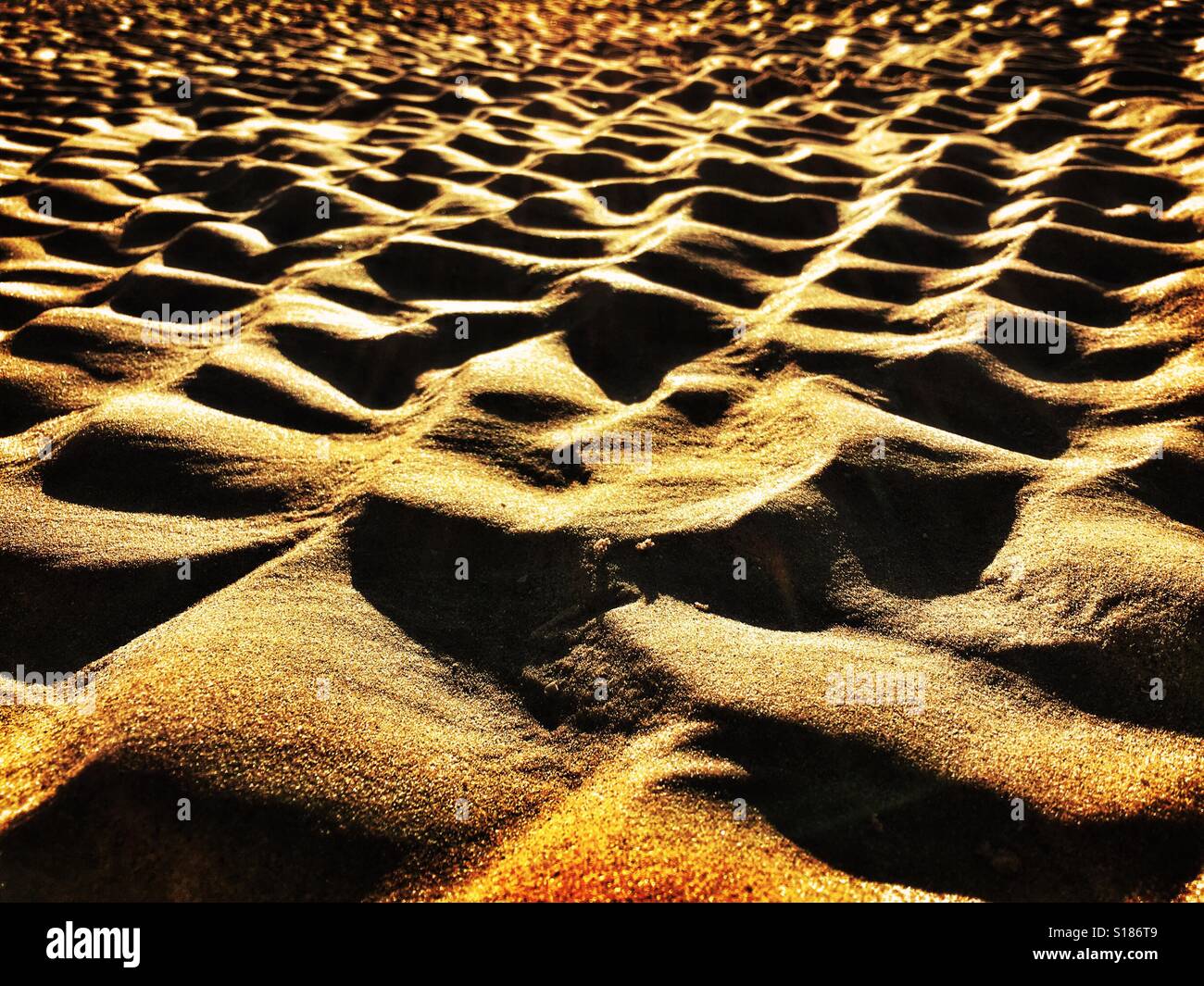 Undulations in sand on beach at low tide with strong side lighting - Smartphone Captured Stock Image