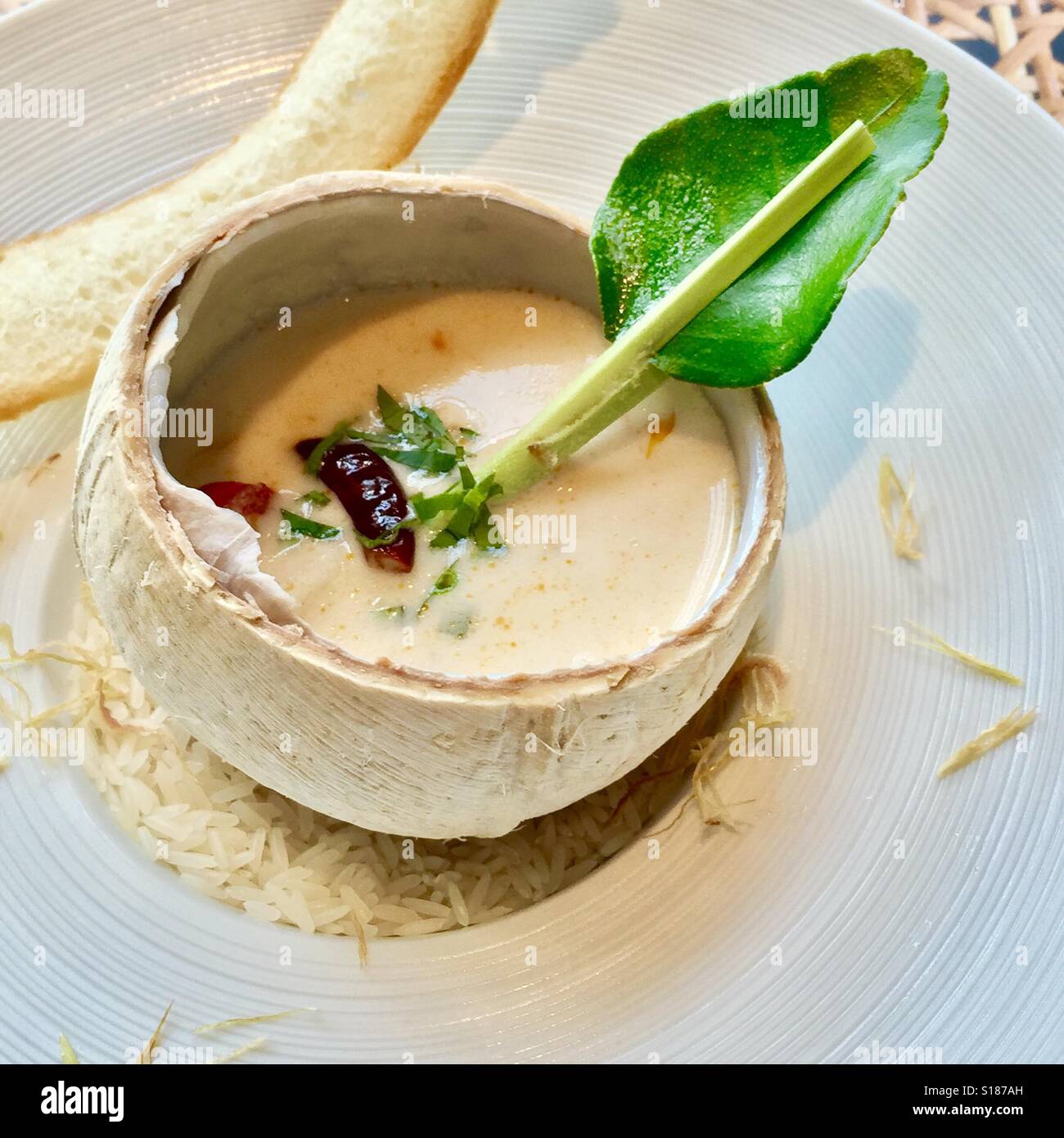 Tom Kha Gai ( Chicken Coconut Soup) served in a coconut shell Stock Photo