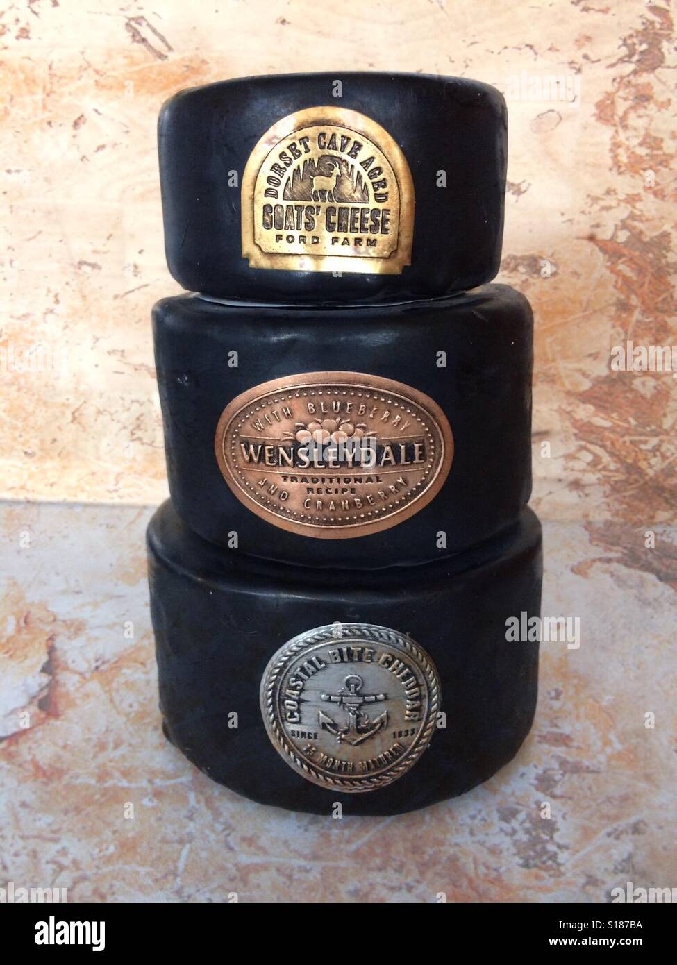 Stack of cheeses with labels and black wax coating. - Smartphone Captured Stock Image