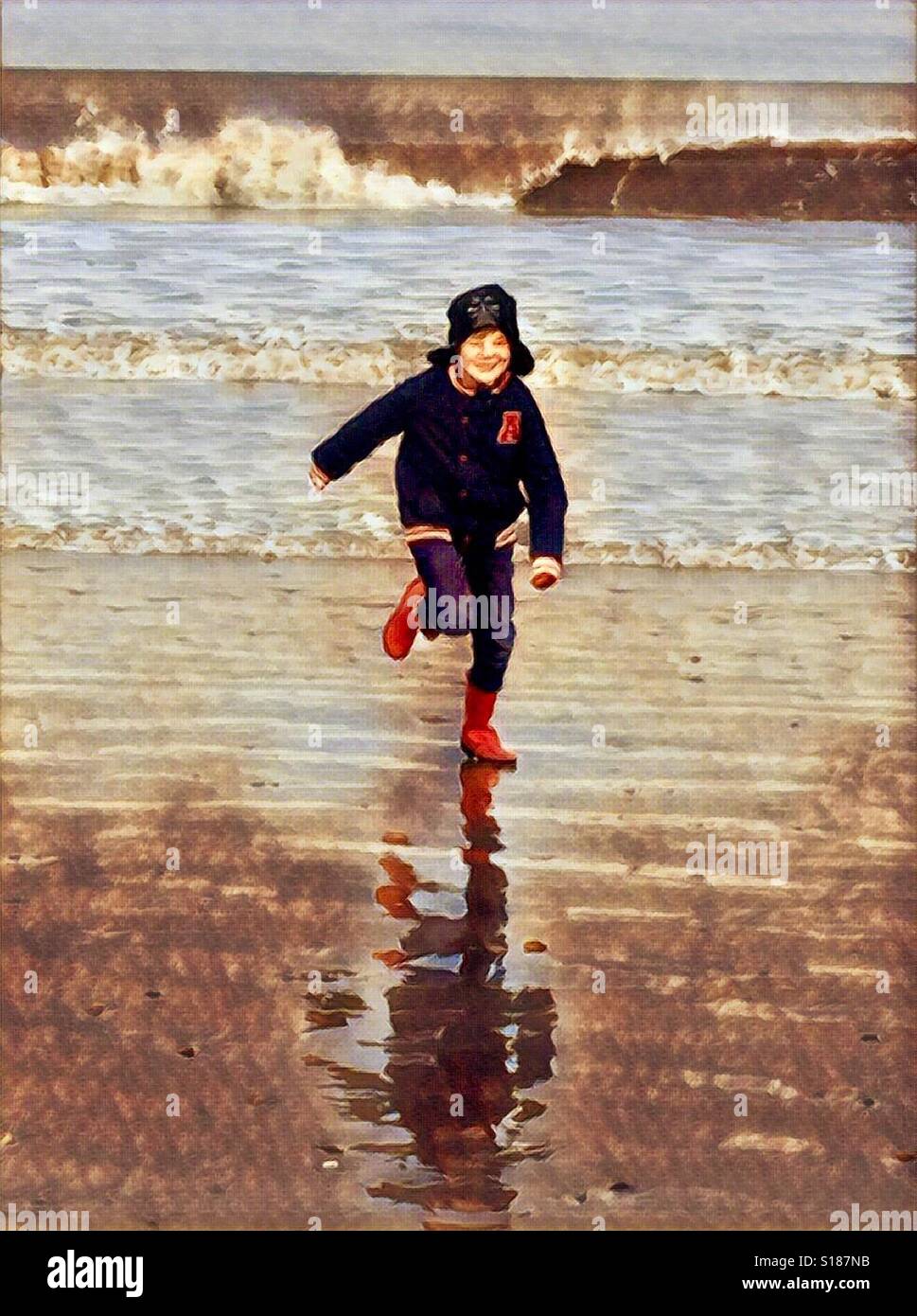 Boy running on a beach in winter Stock Photo