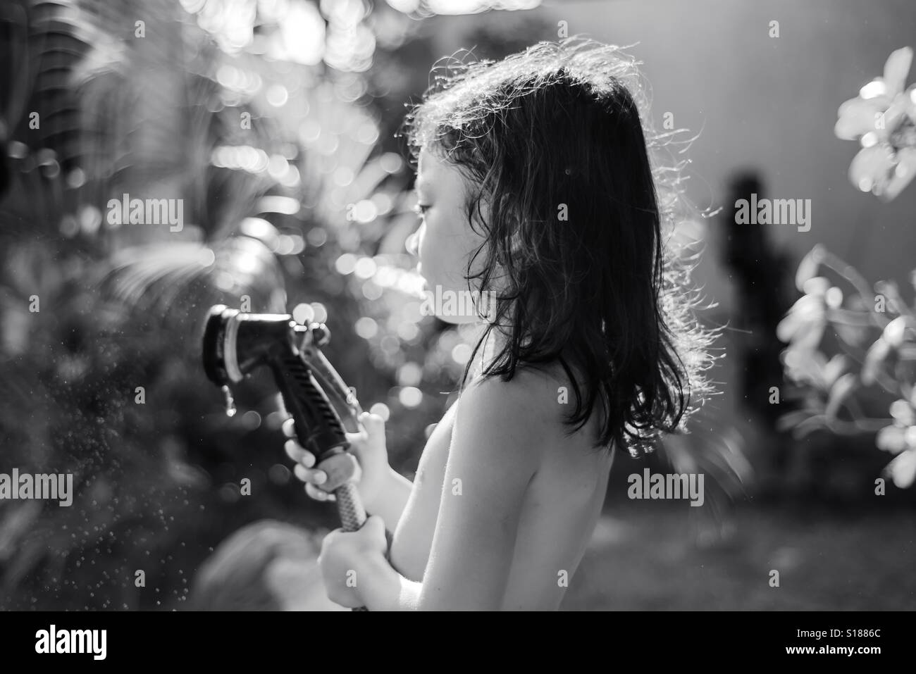 Young girl plays with water spray in black and white Stock Photo