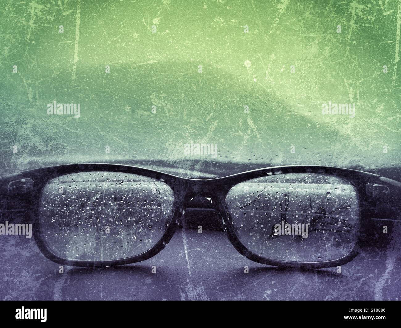 Fogged up and wet eye glasses on dash of car looking into fog and rain