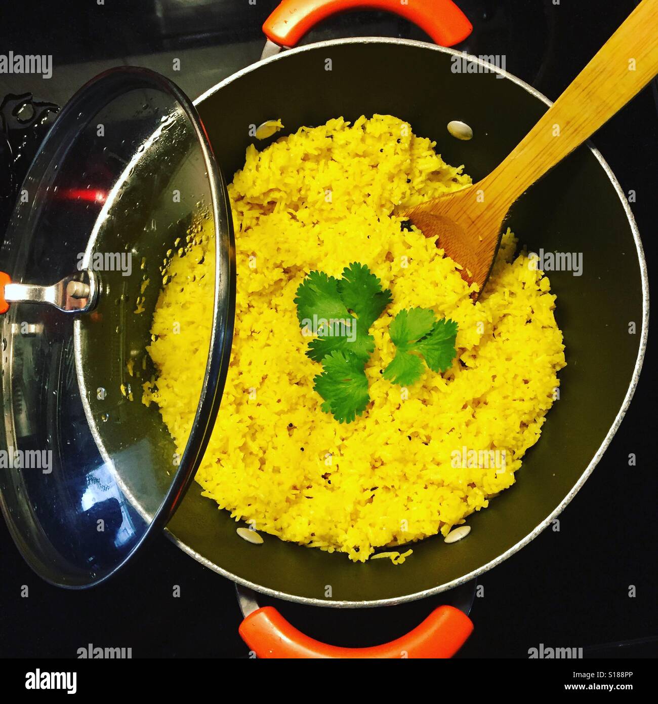 Spanish Rice in an orange and black pot on a black stove with a little touch of green cilantro by K.R. Stock Photo