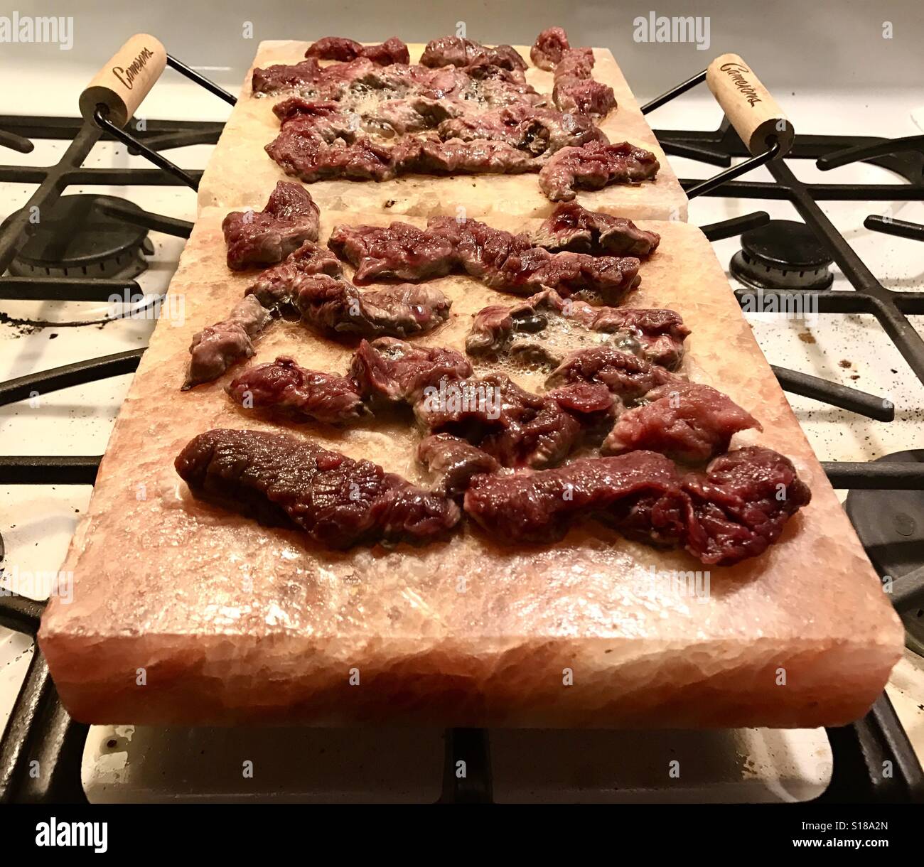 Wild game venison being cooked on pink Himalayan salt blocks Stock