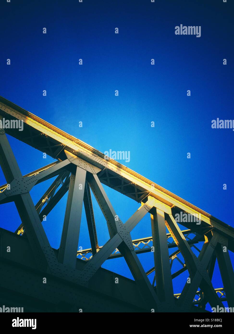 A metal railway bridge lit by golden sunlight - Smartphone Captured Stock Image