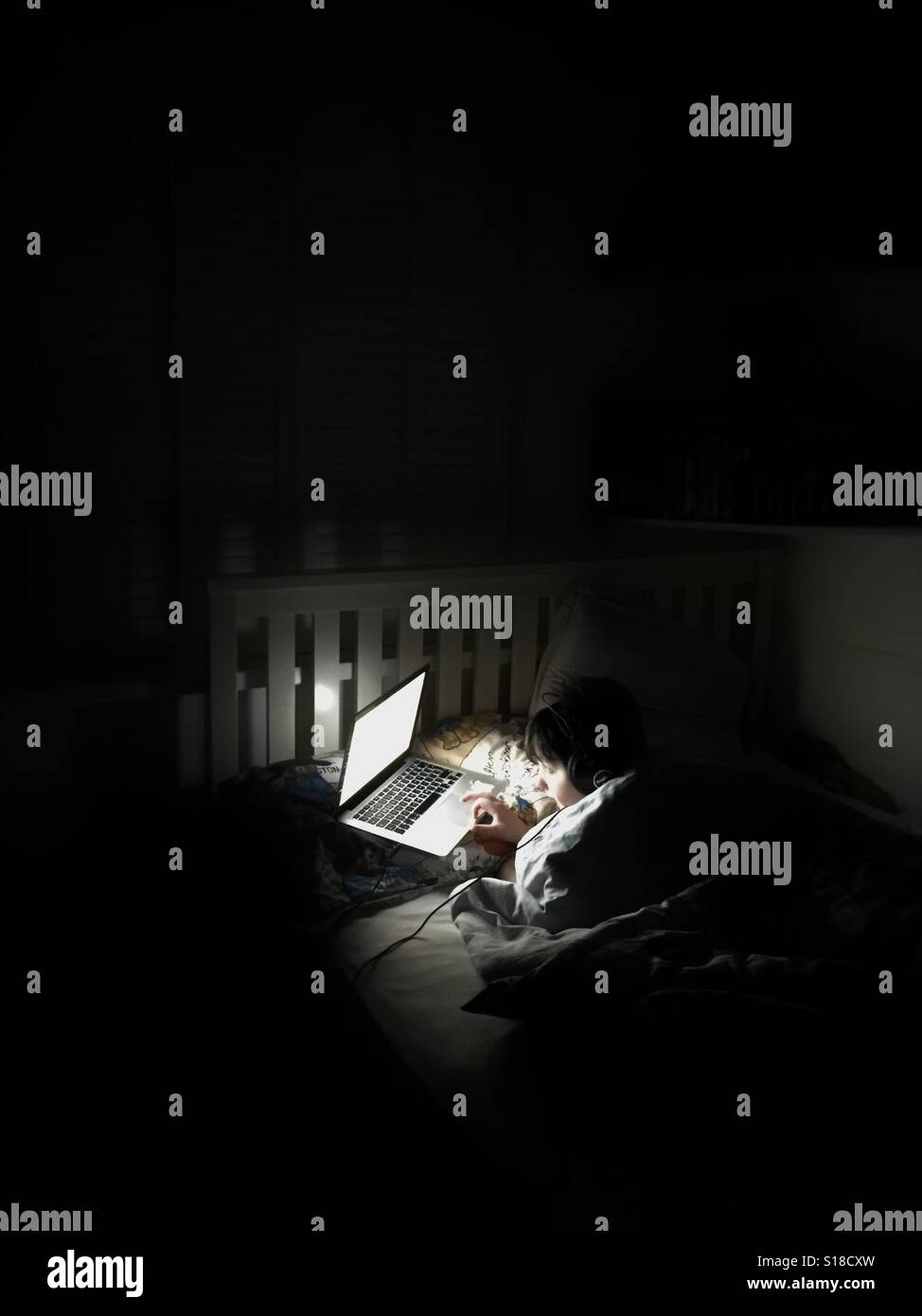 Young boy using computer in bedroom Stock Photo