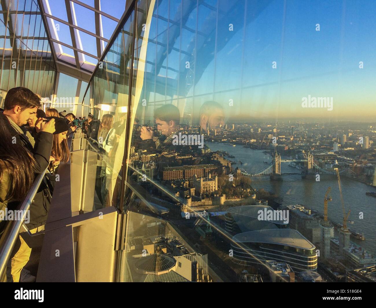 Tourists on the outside viewing platform of 20 fenchurch street or the Walkie talkie building looking at tower bridge and river Thames city of London uk - Smartphone Captured Stock Image