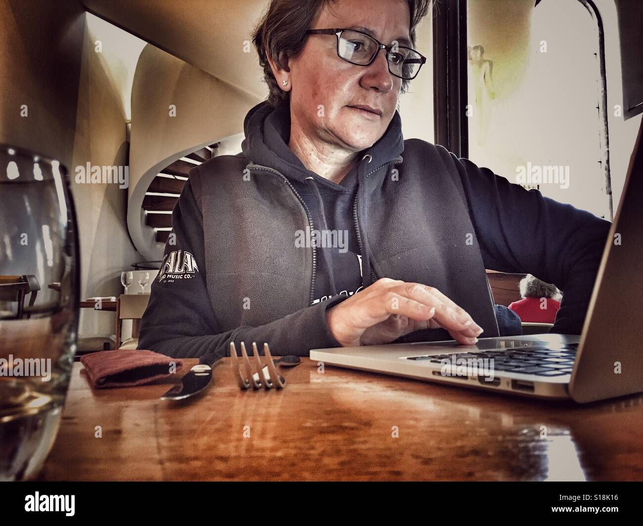 Woman in a restaurant, working on an iMac Apple computer. - Smartphone Captured Stock Image