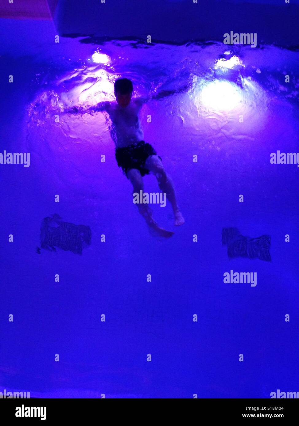 Man swimming in pool at night - Smartphone Captured Stock Image