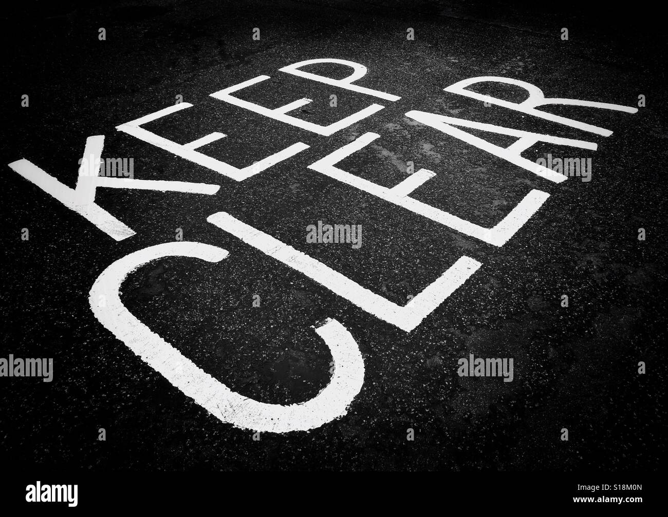 The words 'KEEP CLEAR' are painted onto the tarmac to inform drivers they are not permitted to stop, load, off load or park in this area. An image with multiple uses. Photo Credit - © COLIN HOSKINS. - Smartphone Captured Stock Image