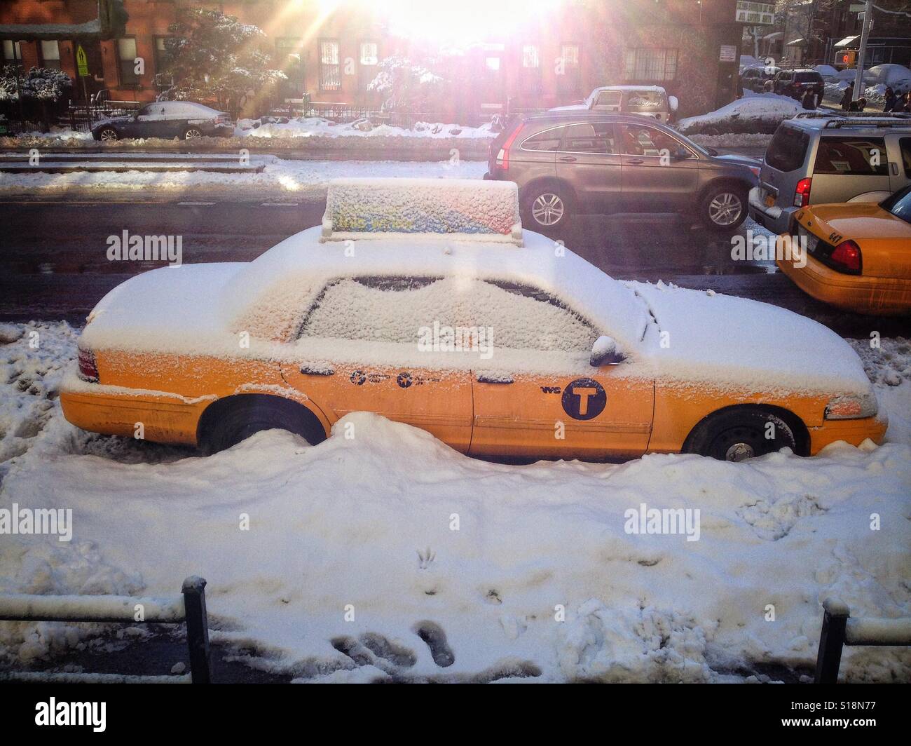 A New York City taxi cab parked on a Brooklyn street is covered with snow after a winter storm. Stock Photo