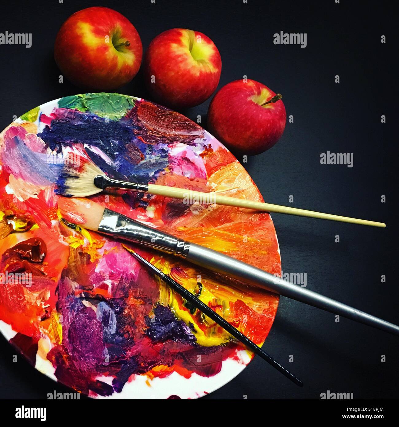 Artists paint palette on a dinner plate with three brushes. Mobile phone photo with some phone or tablet post processing. - Smartphone Captured Stock Image
