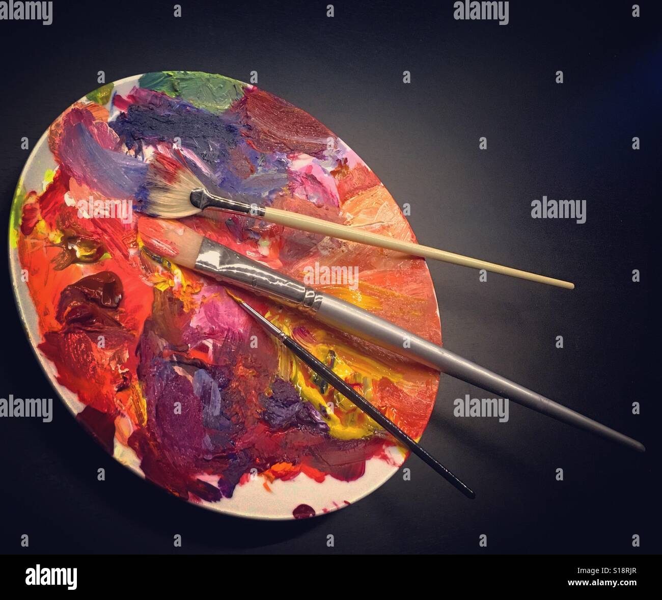 Artists paint palette on a dinner plate with three brushes Stock Photo