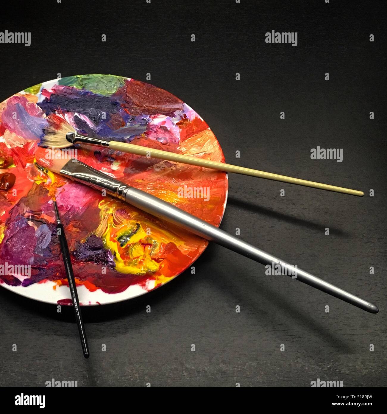Artists paint palette on a dinner plate with three brushes. Mobile phone photo with some phone or tablet post processing. - Smartphone Captured Stock Image
