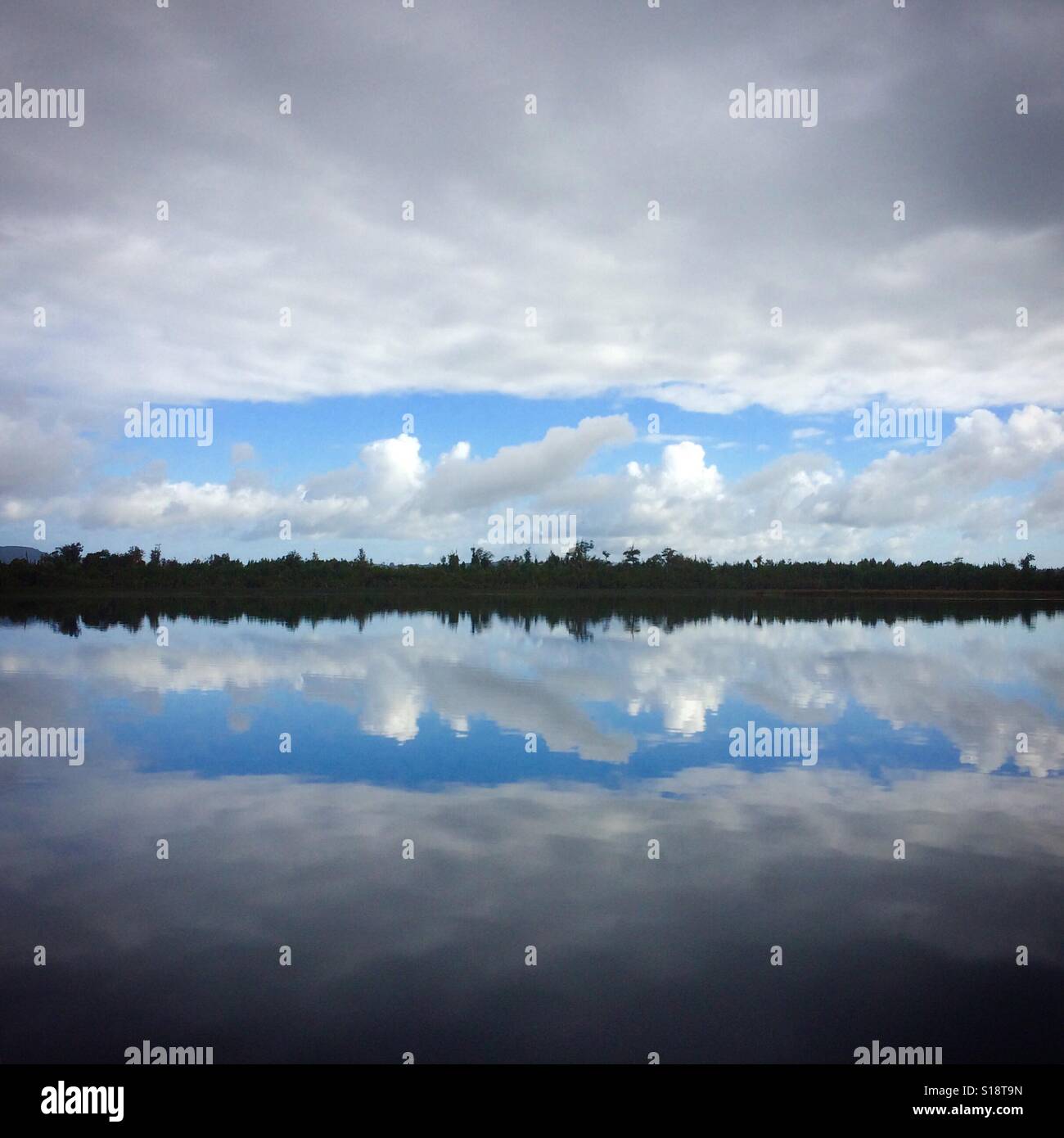 Patch of Blue, cloudy sky reflected in Chepu River, Chiloe Island, Chile - Smartphone Captured Stock Image