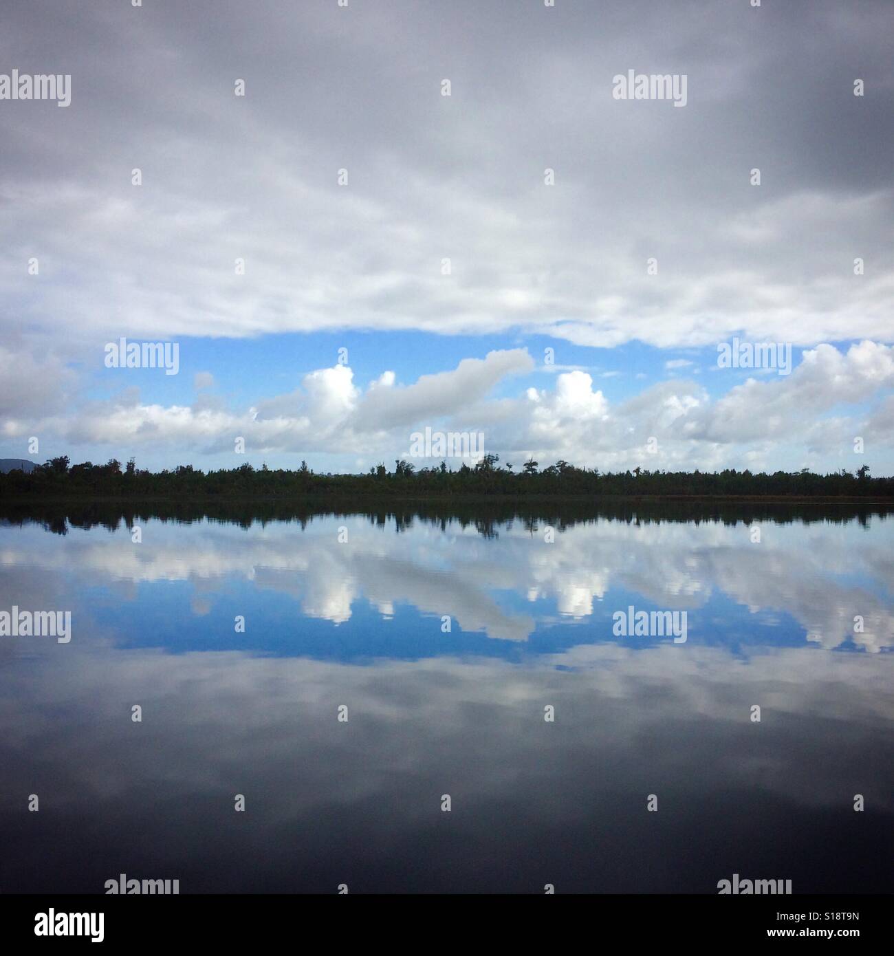 Patch of Blue, cloudy sky reflected in Chepu River, Chiloe Island, Chile Stock Photo