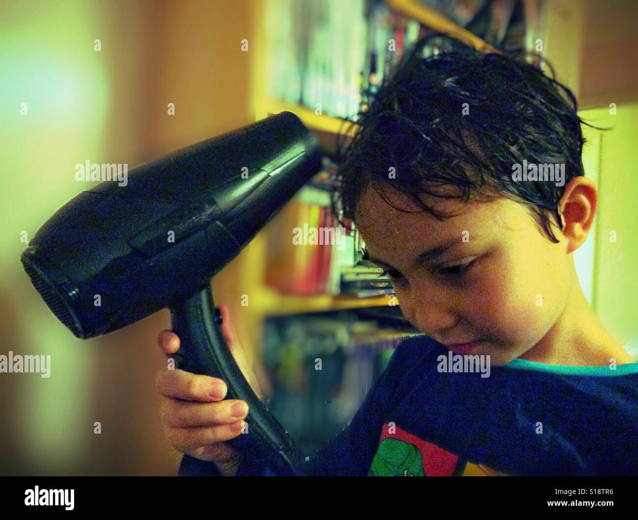 A boy drys his hair with a hair dryer. Stock Photo