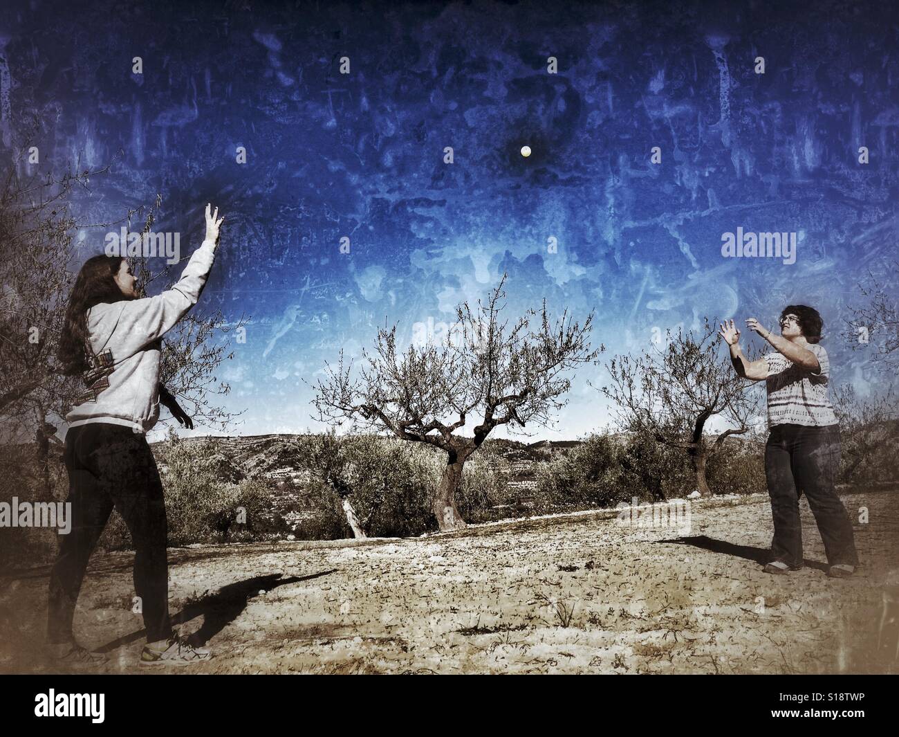 Two teenagers playing catch with a yellow ball. - Smartphone Captured Stock Image
